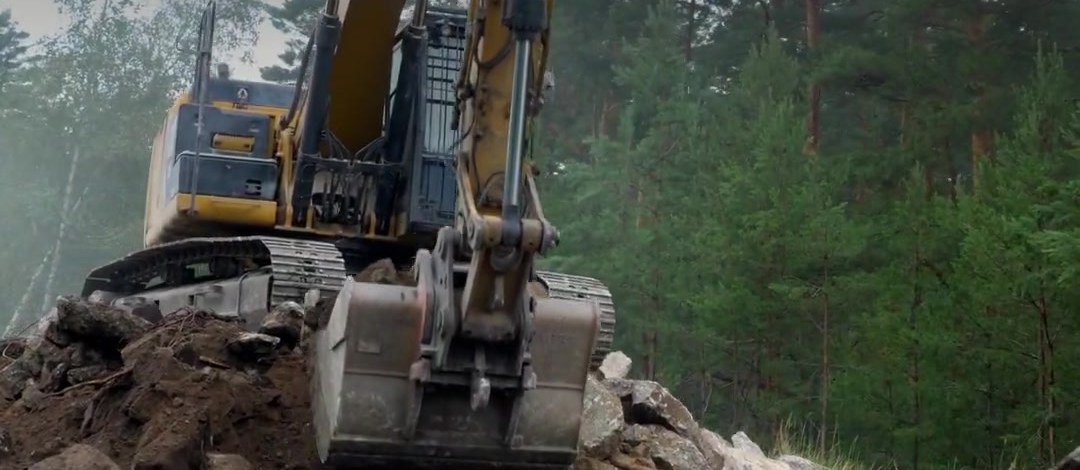 Bagger bricht altes Straßenmaterial zum Recycling